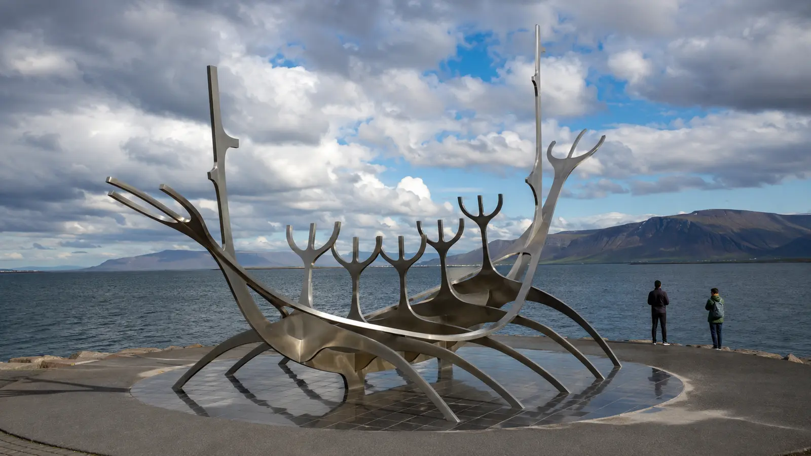 ประติมากรรม Sun Voyager รูปเรือเหล็กริมอ่าวเรคยาวิก โดยมีภูเขาเอสยาอยู่ด้านหลัง