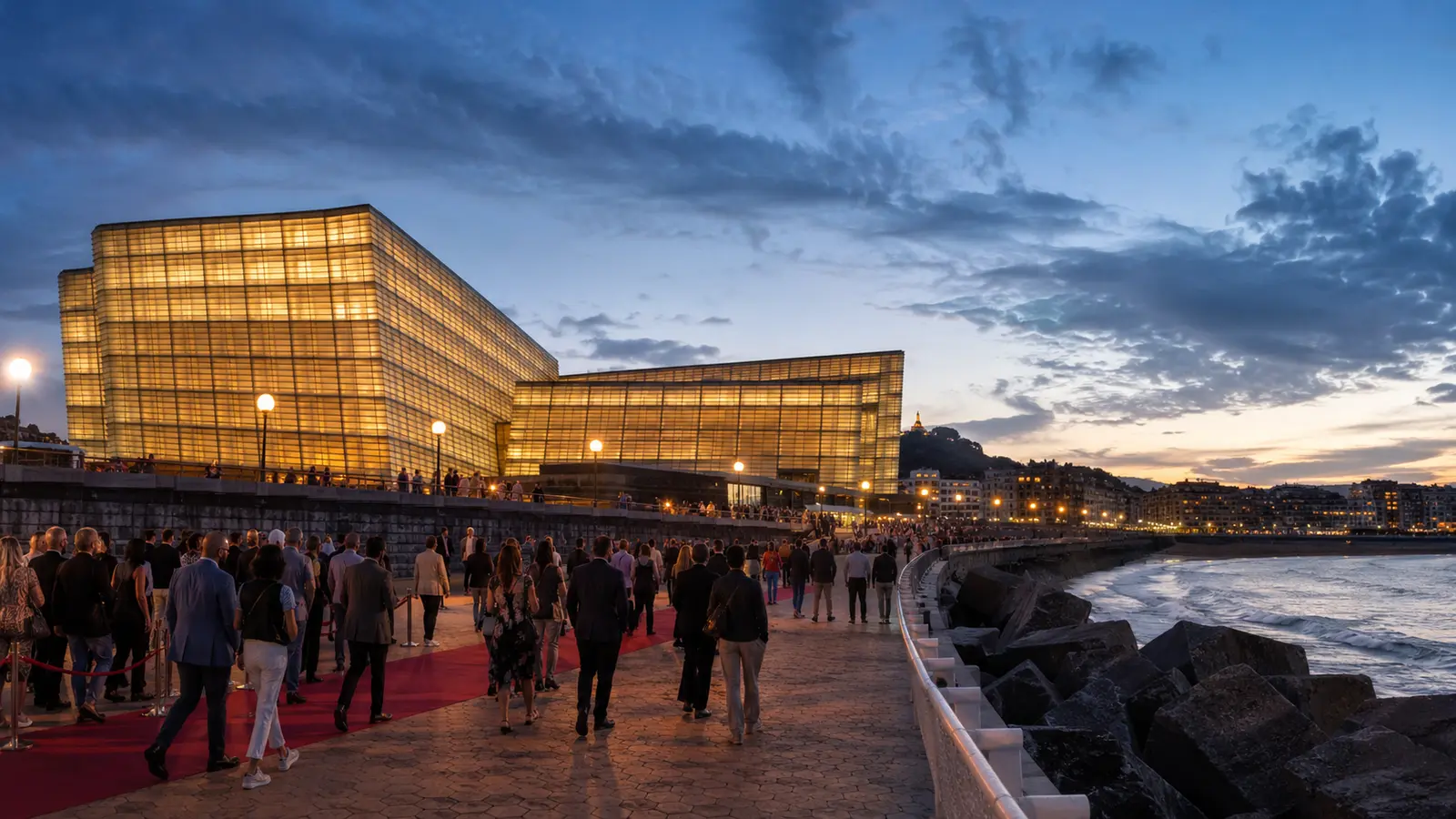 ผู้ชมเทศกาลภาพยนตร์เดินเข้าสู่ศูนย์ประชุม Kursaal ริมหาด Zurriola ในซานเซบาสเตียนช่วงพลบค่ำ